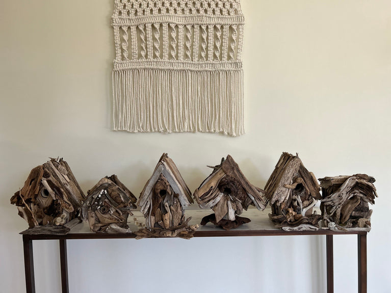Six driftwood birdhouses in a row on a marble table